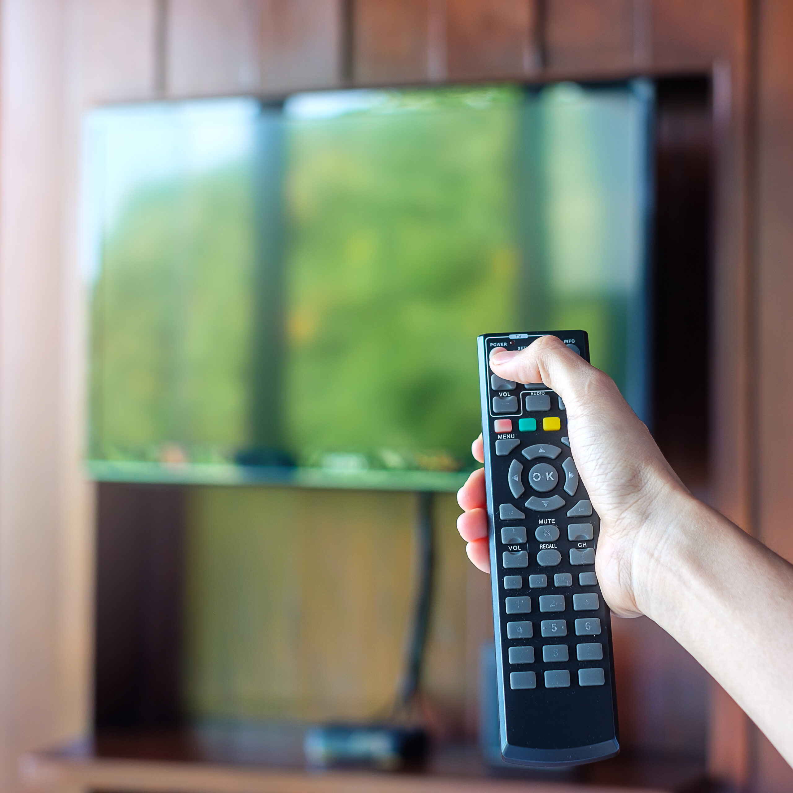 hand using remote controller for adjust Smart TV inside the mode